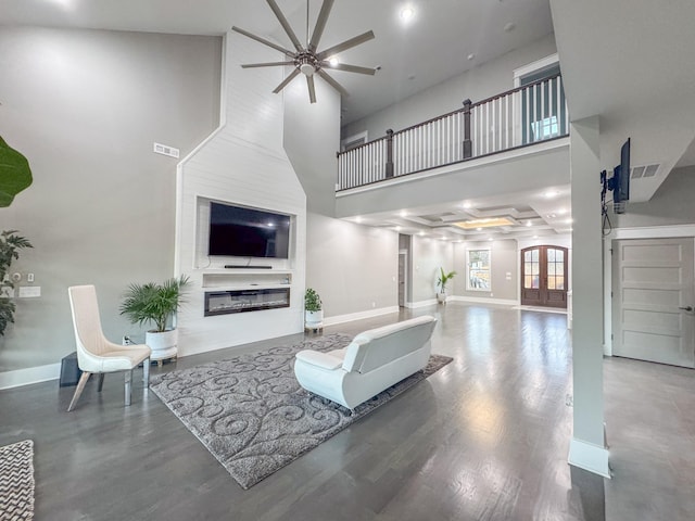 living room with a high ceiling, ceiling fan, wood-type flooring, and a fireplace