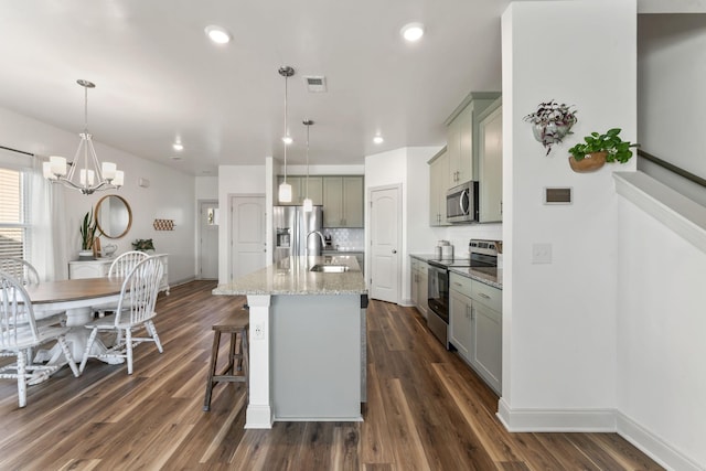 kitchen with stainless steel appliances, tasteful backsplash, hanging light fixtures, and a kitchen island with sink