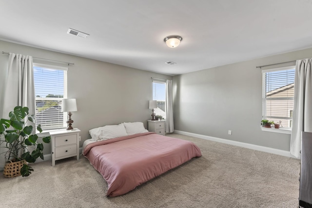 bedroom with multiple windows and light carpet