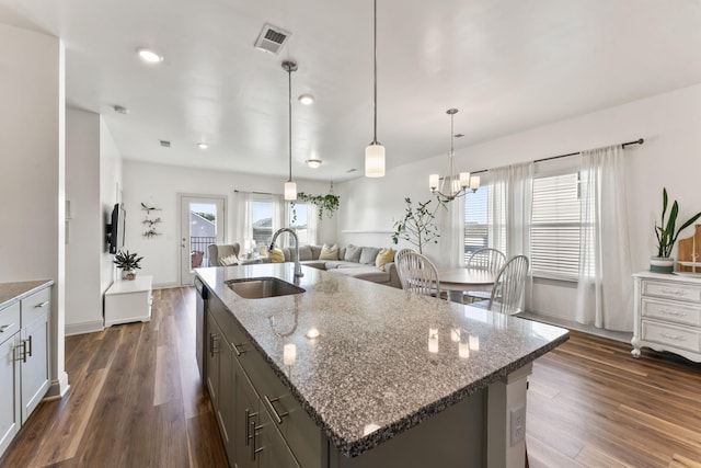 kitchen featuring dark wood-type flooring, light stone countertops, sink, and hanging light fixtures