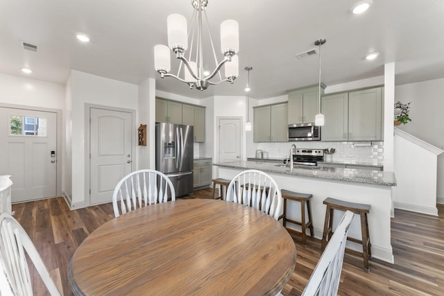 dining area with sink, an inviting chandelier, and dark hardwood / wood-style flooring