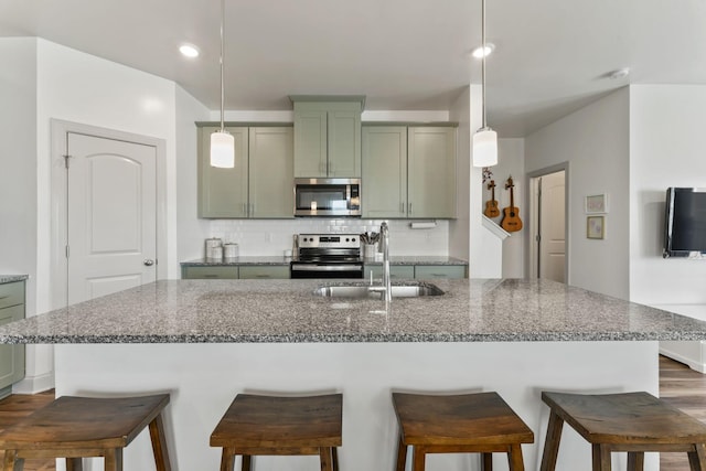 kitchen featuring sink, green cabinets, stainless steel appliances, stone countertops, and decorative light fixtures