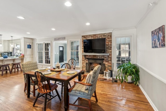 dining space featuring crown molding, a fireplace, and light hardwood / wood-style flooring