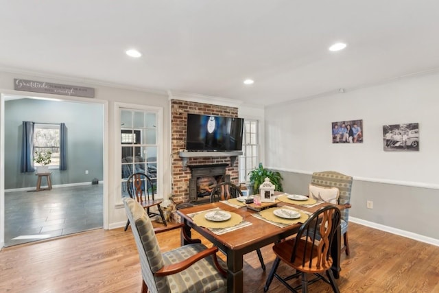 dining area with hardwood / wood-style flooring, crown molding, and a brick fireplace