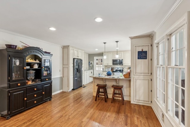 kitchen featuring a kitchen breakfast bar, hanging light fixtures, light stone counters, stainless steel appliances, and light wood-type flooring