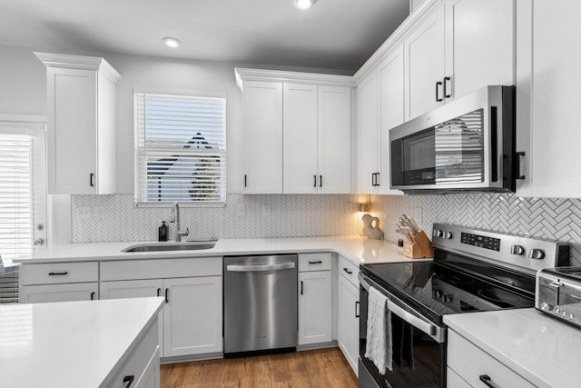 kitchen featuring white cabinetry, sink, backsplash, and stainless steel appliances