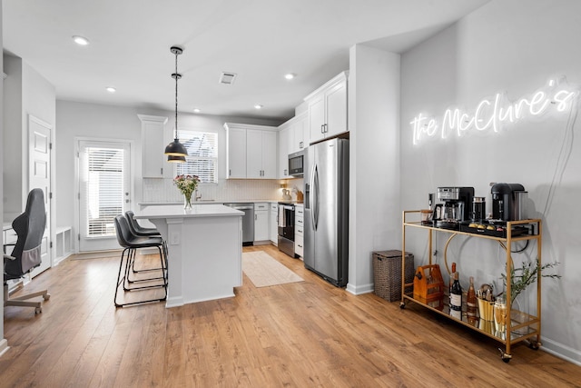 kitchen with pendant lighting, a healthy amount of sunlight, stainless steel appliances, and white cabinets