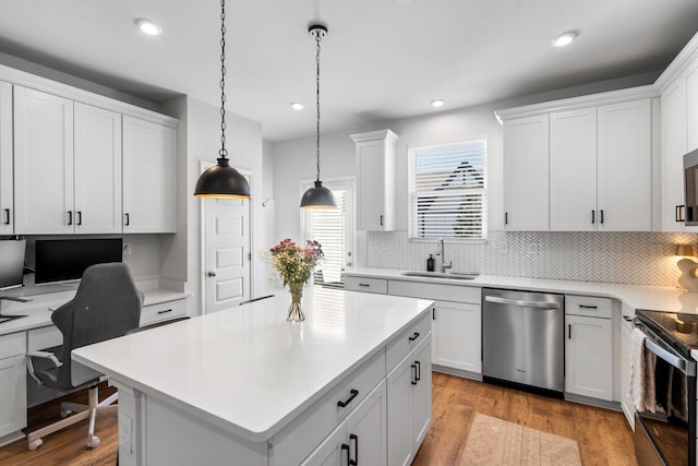 kitchen with stainless steel appliances, a center island, hanging light fixtures, and white cabinets