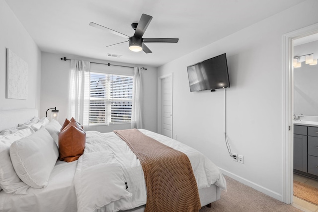 carpeted bedroom with ensuite bathroom and ceiling fan