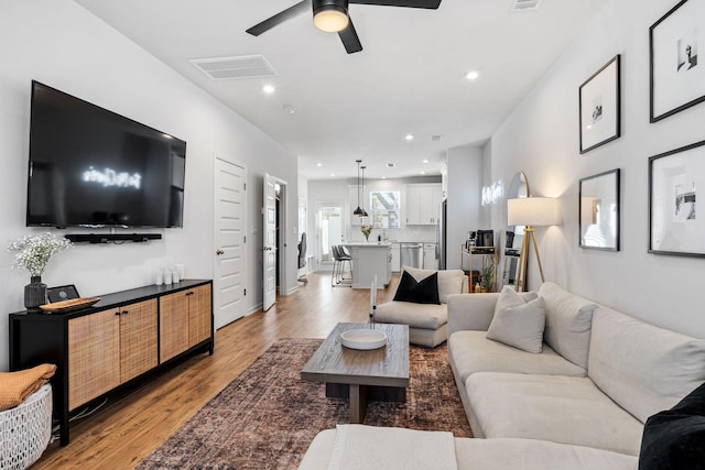 living room with ceiling fan and light wood-type flooring