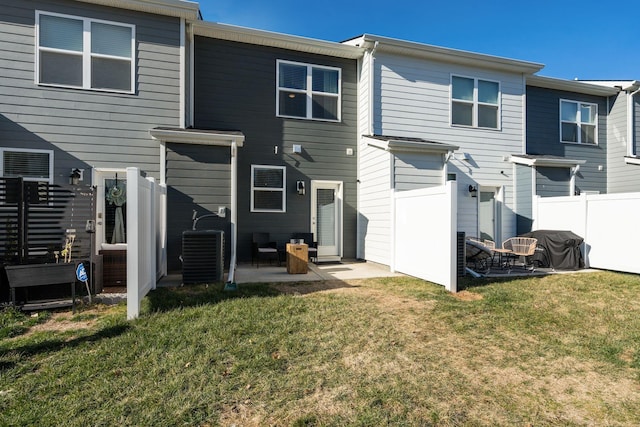 back of property with central AC, a patio, and a lawn