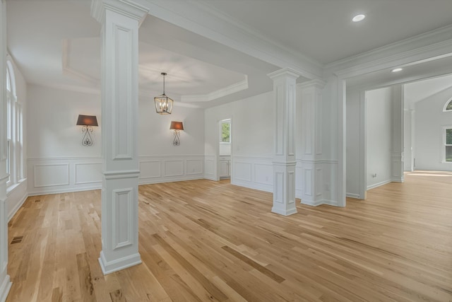 unfurnished living room featuring crown molding, light hardwood / wood-style floors, and ornate columns