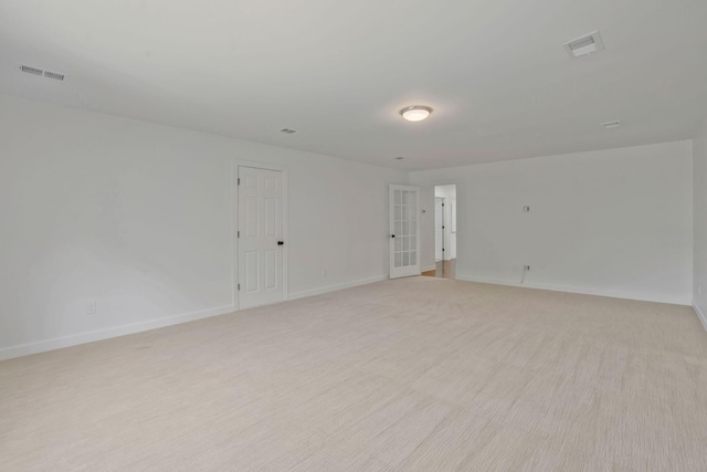 spare room featuring light carpet and french doors