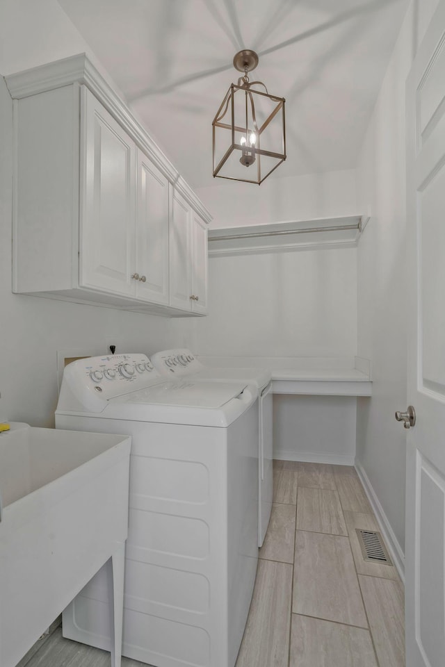 laundry room featuring an inviting chandelier, cabinets, sink, and washing machine and clothes dryer