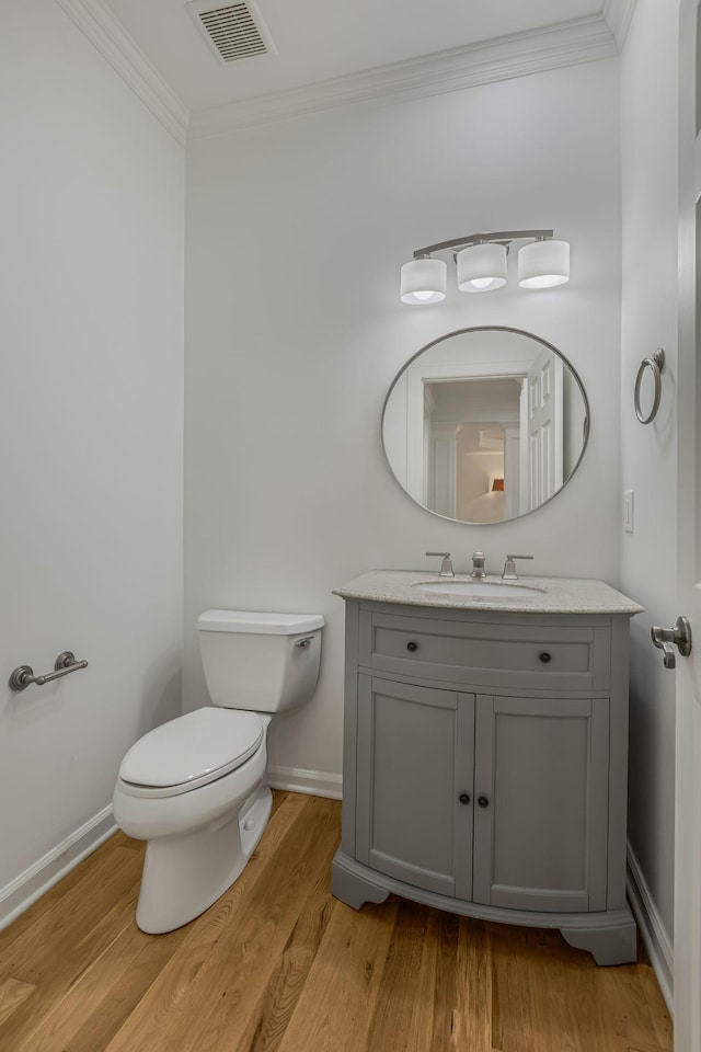 bathroom with vanity, crown molding, wood-type flooring, and toilet