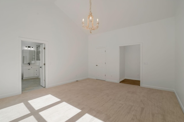 carpeted empty room featuring high vaulted ceiling and a chandelier