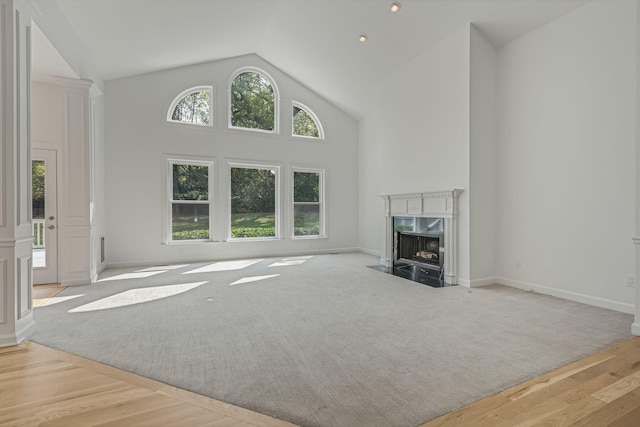 unfurnished living room featuring light hardwood / wood-style flooring, high vaulted ceiling, and a premium fireplace