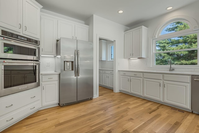 kitchen featuring sink, light hardwood / wood-style flooring, white cabinets, and appliances with stainless steel finishes