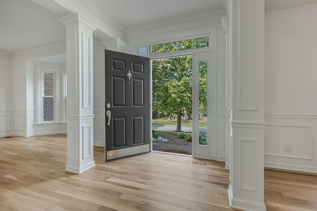 entryway featuring crown molding, light wood-type flooring, and ornate columns