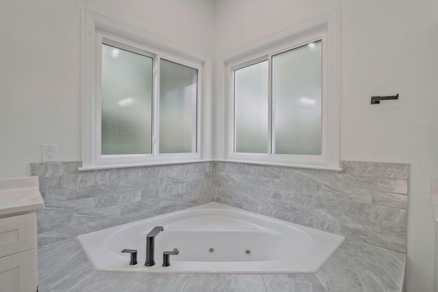 bathroom with vanity and tiled tub