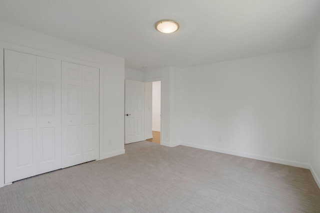 unfurnished bedroom featuring light colored carpet and a closet