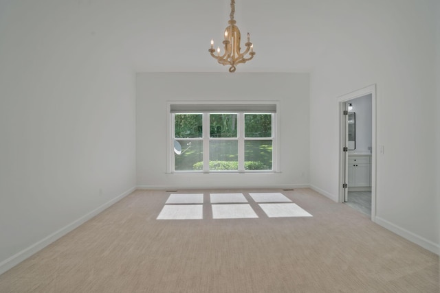 empty room with an inviting chandelier and light colored carpet