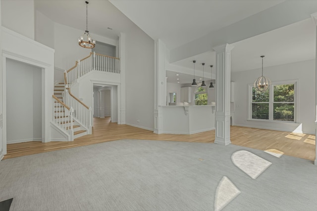 unfurnished living room with ornate columns, light hardwood / wood-style flooring, and a notable chandelier