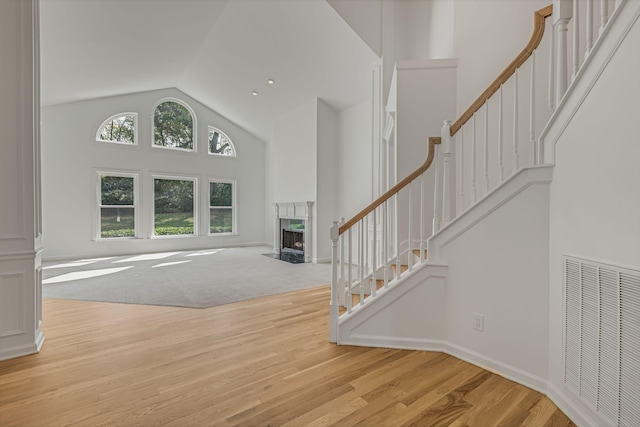 unfurnished living room featuring high vaulted ceiling and light wood-type flooring