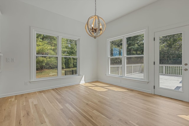 unfurnished dining area with a chandelier and light hardwood / wood-style flooring