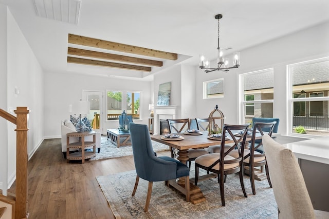 dining space with hardwood / wood-style floors, beam ceiling, and a chandelier