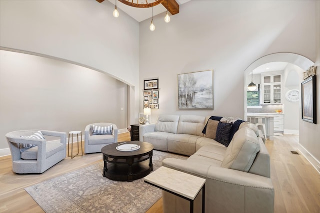 living room with light hardwood / wood-style flooring, high vaulted ceiling, and beamed ceiling