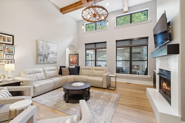 living room featuring a fireplace, plenty of natural light, beam ceiling, and light wood-type flooring