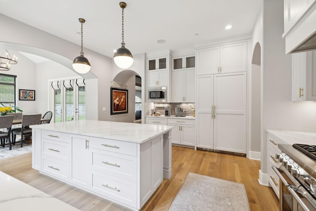 kitchen featuring white cabinetry, stainless steel appliances, light stone countertops, and pendant lighting