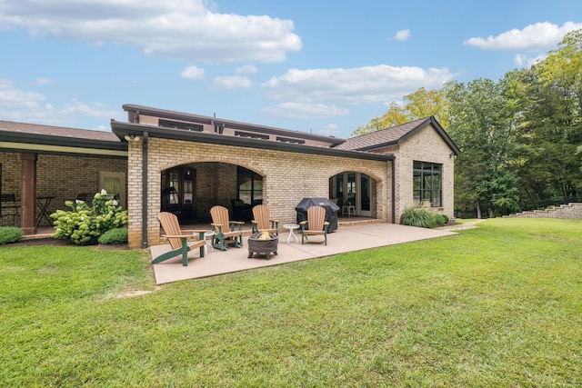 back of property featuring a lawn, a patio, and an outdoor fire pit