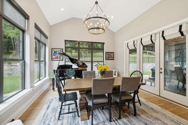 dining area with an inviting chandelier, lofted ceiling, and light wood-type flooring