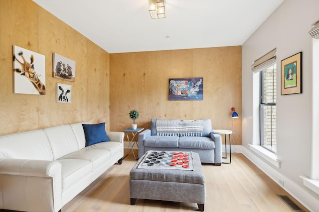 living room with light wood-type flooring and wood walls