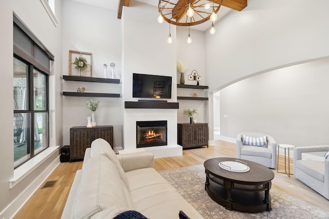 living room with beam ceiling, light hardwood / wood-style floors, and a wealth of natural light