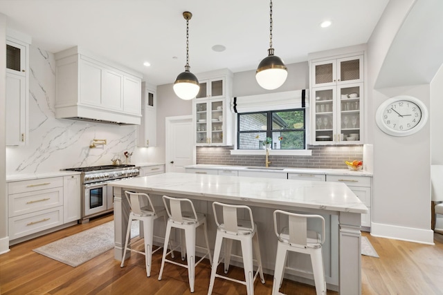 kitchen featuring white cabinetry, double oven range, a center island, and light wood-type flooring