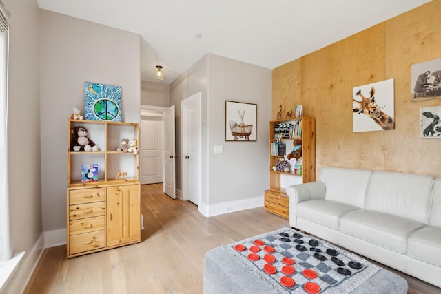 living room with light hardwood / wood-style floors and wood walls