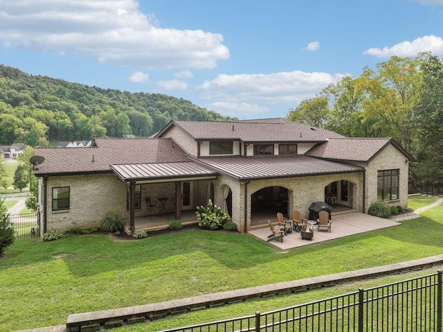 back of property featuring a fireplace, a patio area, and a lawn