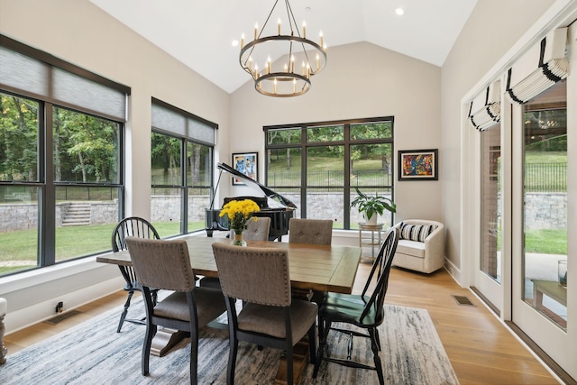 dining area with a notable chandelier, lofted ceiling, and light wood-type flooring