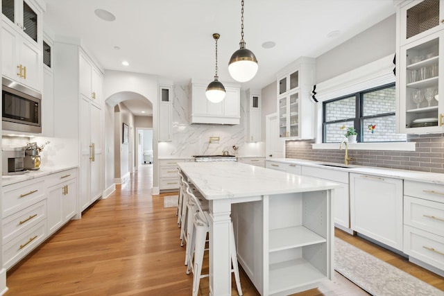 kitchen with pendant lighting, stainless steel microwave, a center island, and white cabinets