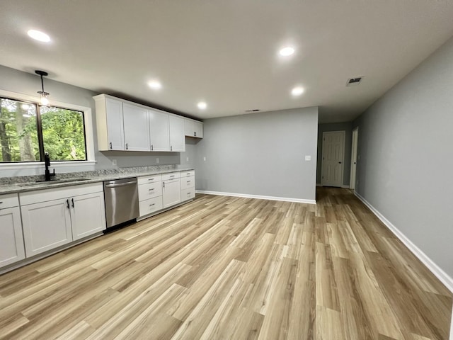 kitchen with sink, dishwasher, light stone counters, white cabinets, and light wood-type flooring