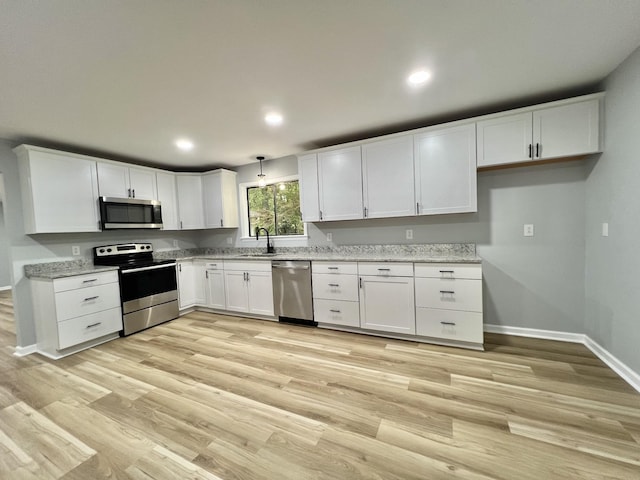 kitchen with white cabinetry, sink, stainless steel appliances, and light hardwood / wood-style floors