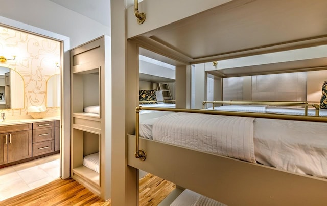 bedroom with ensuite bathroom, sink, and light hardwood / wood-style floors