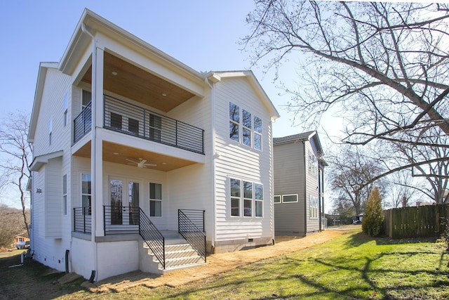 rear view of property featuring a yard, a balcony, and ceiling fan