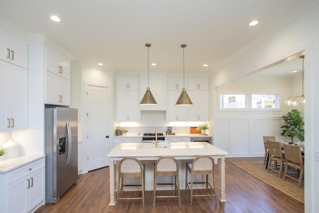 kitchen featuring decorative light fixtures, appliances with stainless steel finishes, dark hardwood / wood-style floors, an island with sink, and white cabinets