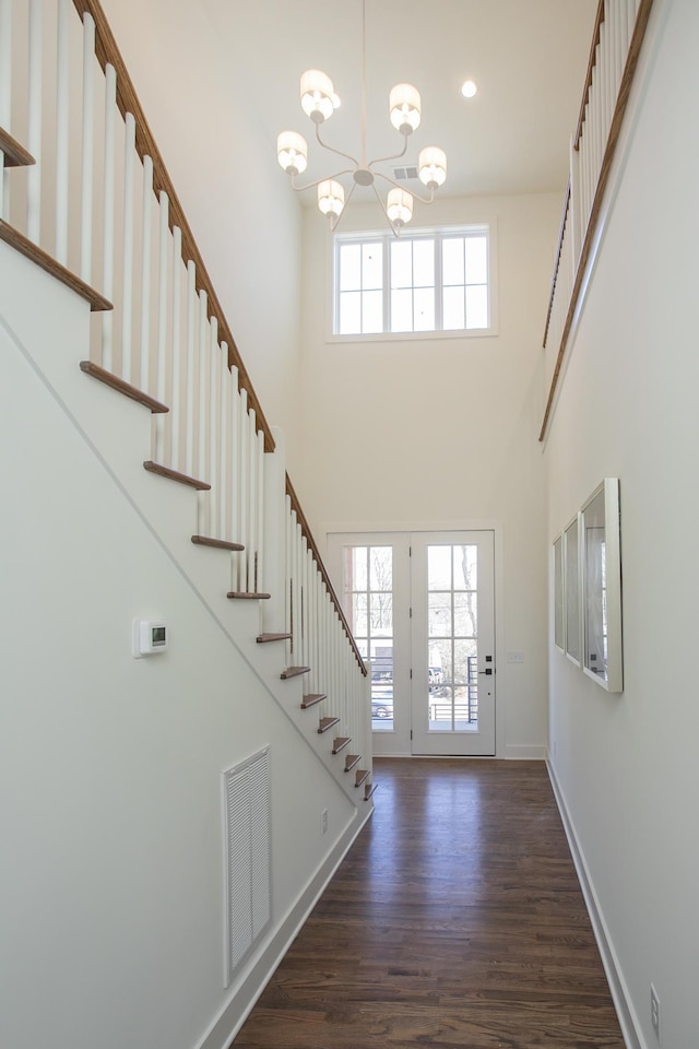 foyer entrance featuring a towering ceiling, an inviting chandelier, and dark hardwood / wood-style flooring