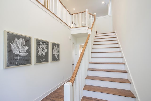 staircase with hardwood / wood-style flooring and a high ceiling