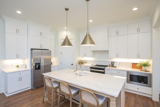 kitchen with stainless steel appliances, hanging light fixtures, a center island with sink, and white cabinets